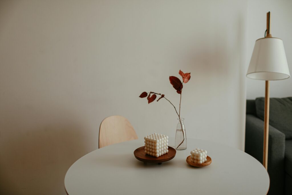 Tendenze arredamento 2026: L'Equilibrio Perfetto tra Natura, Design e Silenzio Visivo A minimalist interior with decorative candles on a table and a lamp in the background, perfect for cozy home inspiration.